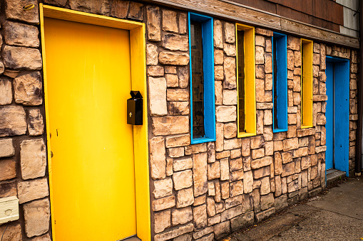 A charming stone house featuring striking blue and yellow doors and windows, evoking the vibrant hues of the flags of Sweden and Ukraine.