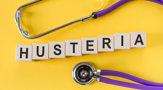 The word hysteria made from wooden cubes on a yellow table with a stethoscope. Medical concept.
