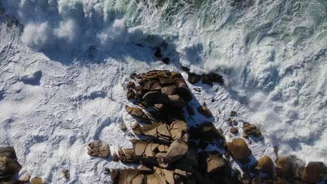 Top-down view of powerful storm waves rolling onto the rocky shore