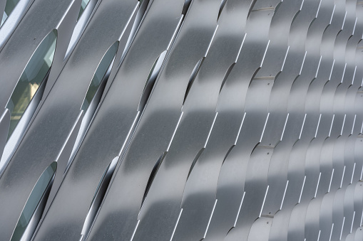 Close-up photo of silver gray angled exterior aluminum louvers  over a buildings windows - glazing.
