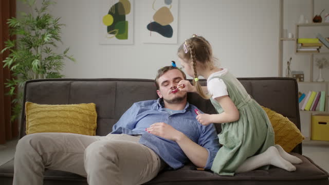 Relaxed Father Gets a Makeover from His Young Daughter with Lipstick and Hair Clips
