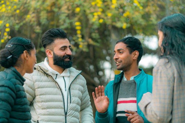A happy multiracial group of friends gathers in a city park to have fun and enjoy talking together.