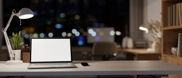 istock An office desk features a laptop computer mockup in a modern skyscraper office at night. 2092935098