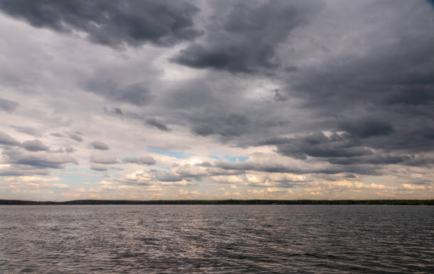 Blue lake with cloudy sky, natural background. Lake with forest on the shores at summer