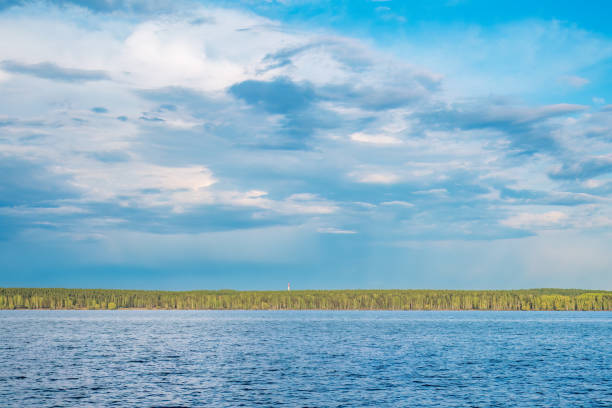 Blue lake with cloudy sky, natural background. Lake with forest on the shores at summer