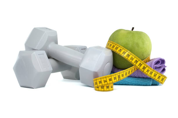 istock Two gray dumbbells and green apple with a tape measure 2092988481