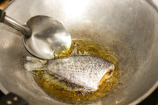 Pictures of food preparing with fried fish in the kitchen with cooking concept.