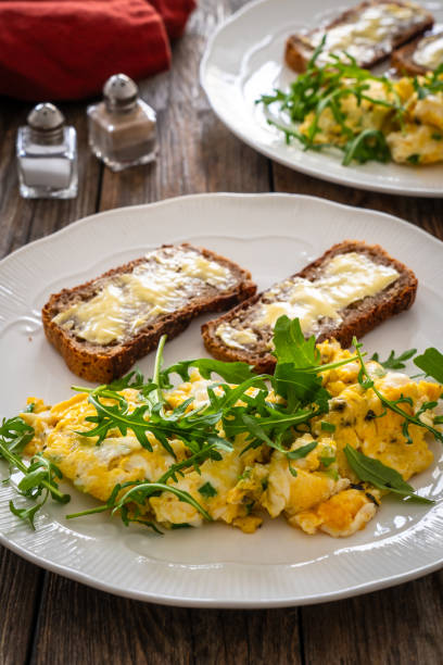 istock Continental breakfast -  scrambled eggs with arugula and toasted bread on wooden table 2093165596