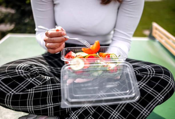 Taking a break eating healthy salad in plastic packaging