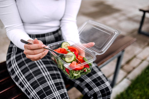 Taking a break eating healthy salad in plastic packaging