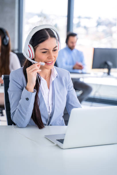 istock Customer support agent woman in headset with microphone talking to client and using laptop at call center. 2093216562