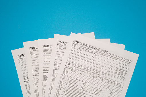 Top view of Forms 1040 U.S. Individual income tax return on a blue background. Space for text.