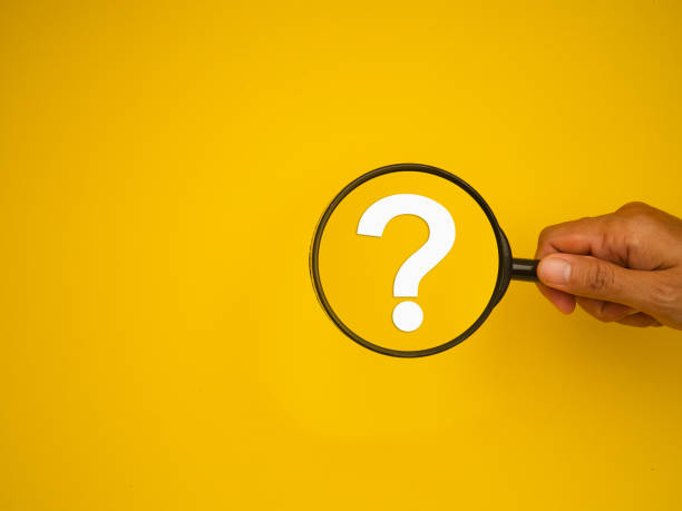 istock Hand holding a magnifying glass with a white question mark symbol against a yellow background. 2093223399