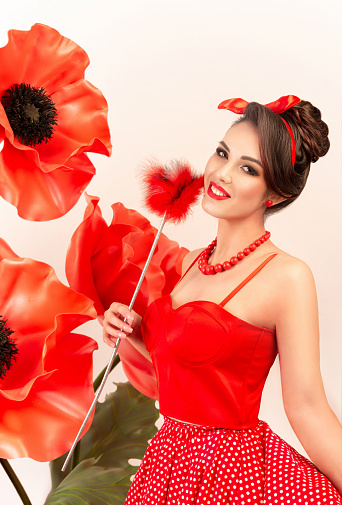Beautiful female portrait in a fairy-tale image with large flowers of red poppies. Making full-length artificial flowers.