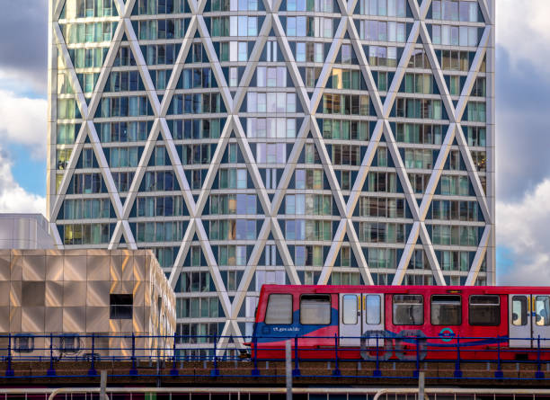 London, United Kingdom - February 26, 2024: Red train passing by the modern office buildings in Canary Wharf, London