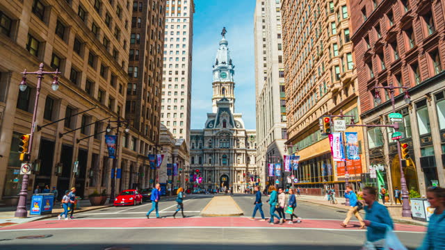 Time lapse of Philadelphia's landmark historic City Hall with traffic car and crowd pedestrian tourist crossroad city street in Philadelphia, Pennsylvania, United States
