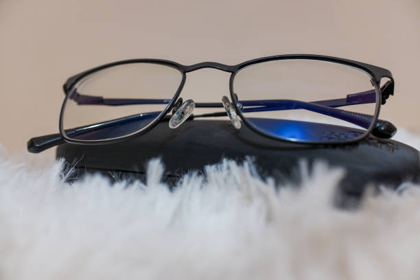 A pair of glasses with a black frame on a black box with a fur carpet background.