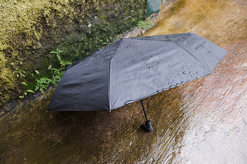 An open black umbrella against a wet floor in the background.