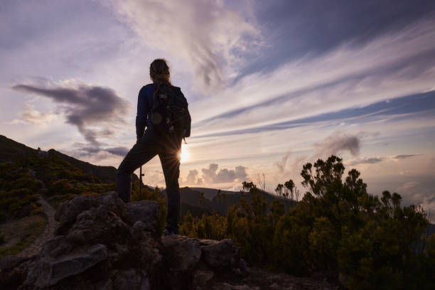 istock Back view of a female backpacker standing on a mountain at sunset. 2093273035