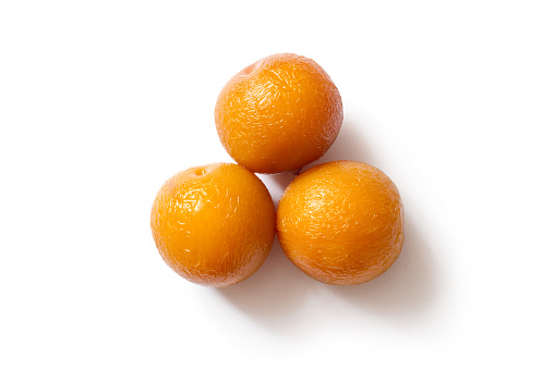 Three yellow canned plums on a white background. Close-up of plums. With a shadow.