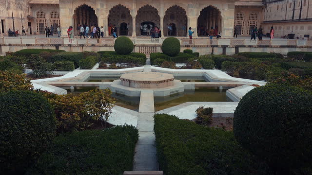 An interior landscaped courtyard and garden with the front view of Sheesh Mahal inside the Amber Fort