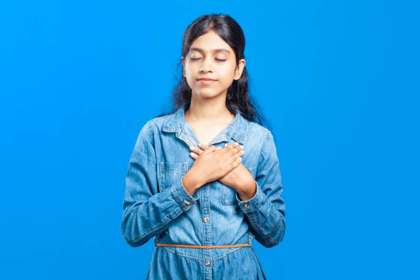 istock calm indian girl resting her hands on heart for inner peace while standing against seamless background 2093312277