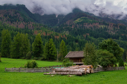 A wooden fence in front of a forest house with mountains and trees in San Candido, South Tyrol, Italy.