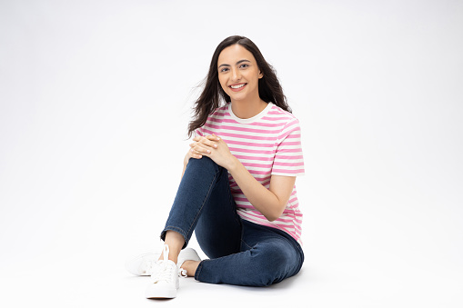 Full length body size photo of young girl sitting on floor wearing jeans denim t-shirt footwear isolated over white background
