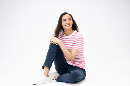 Full length body size photo of young girl sitting on floor wearing jeans denim t-shirt footwear isolated over white background
