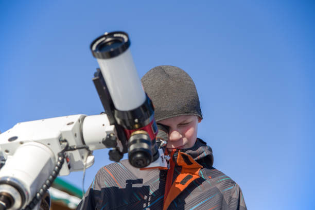 A boy observes the sun through a solar telescope.