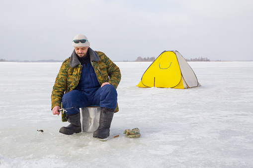 A man fishes on a frozen lake.