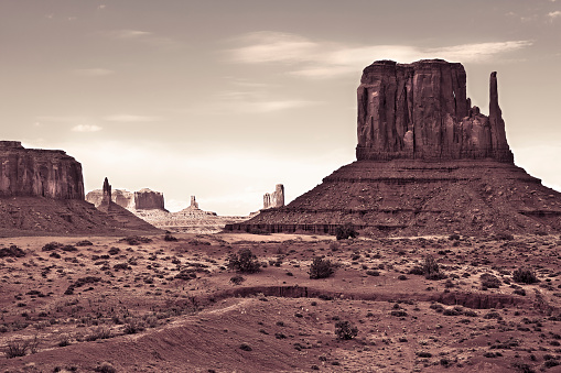 The Monument Valley in UtahArizona state with the crossing road in the desert - The valley is considered sacred by the Navajo Nation - USA - Sepia toned