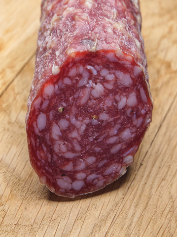 A piece of sausage on a wooden surface, a close-up shot. Smoked sausage on a wooden background.