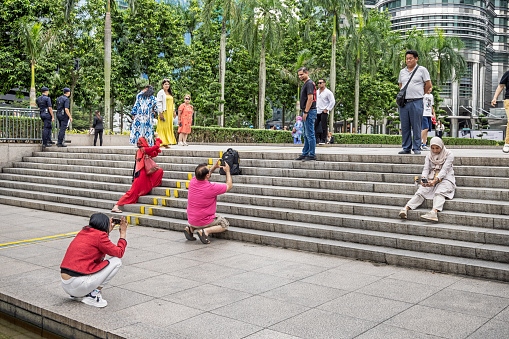 Petronas Towers, Kuala Lumpur, Malaysia - January 8th 2024:  People having fun taking photographs of each other in front of the famous towers in the Malaysian capital