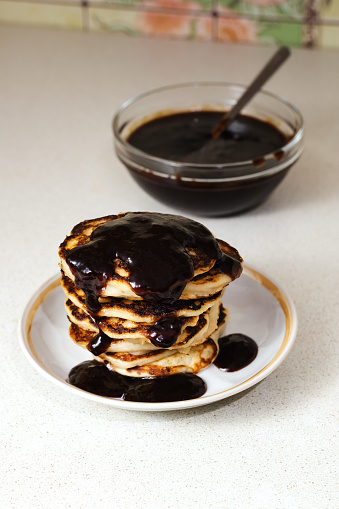 Stack of american pancakes or fritters with jam in plate on white table, delicious dessert for breakfast.
