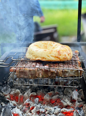 Outdoor barbecue. Meat and fresh pita bread on a grill over hot coals