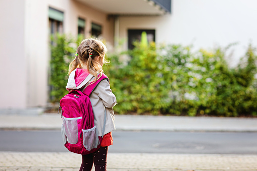 Cute little preschool girl going to playschool. Healthy toddler child walking to nursery school and kindergarten. Happy child with backpack on the city street, outdoors