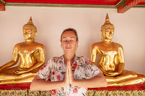 She makes a namaste prayer pose with hands, happy to discover the gems in Asia