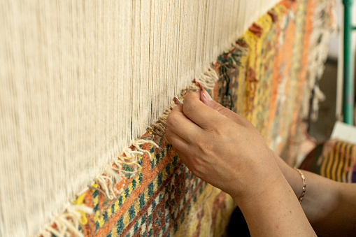 a woman weaving a traditional carpet