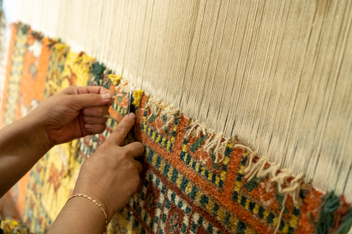 a woman weaving a carpet