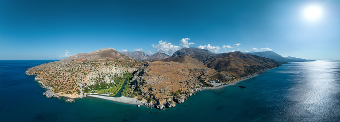 Panoramic view of Preveli gorge with river, palm tree forest and mountains in the background (Crete, Greece).