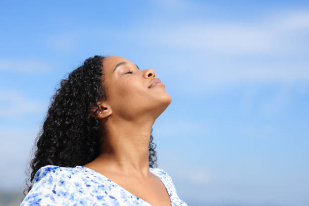istock Black woman breathing fresh air with blue sky 2093512121