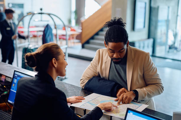 istock Happy hotel receptionist assisting African American man in finding direction on city map. 2093527399