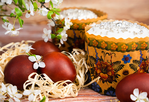 Festive composition with colored eggs and Easter cakes decorated with white icing. Close-up. Selective focus.