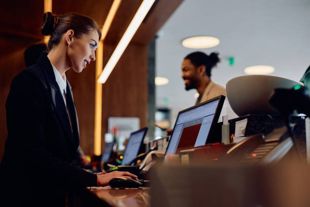 sorridente direttore d'albergo che lavora su un computer alla reception. - albergo foto e immagini stock