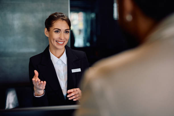 Happy female receptionist serving a guest at the hotel. Copy space.