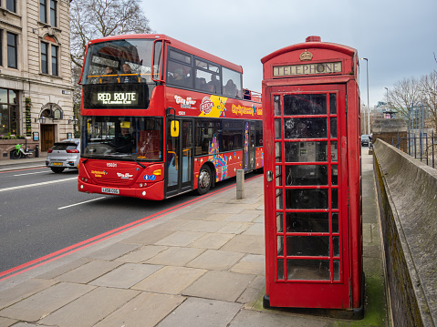 Young voman tourist, commuter in the city of London, exploring London, walking around, taking photos of famous places. Young travel blogger exploring new city. Young woman taking photos of the famous places in London with her phone, taking a selfie with a red bus.