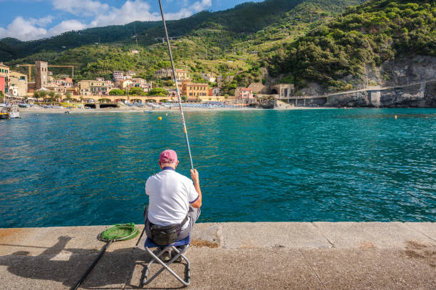 A man is fishing in the pier of Monterosso town