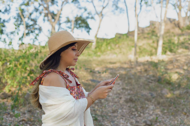 istock Woman walking in a public garden using her cell phone. Sunny day. 2093578091