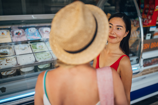 Two women are choosing ice cream flavors and toppings at the ice cream truck and can't wait to refresh themselves